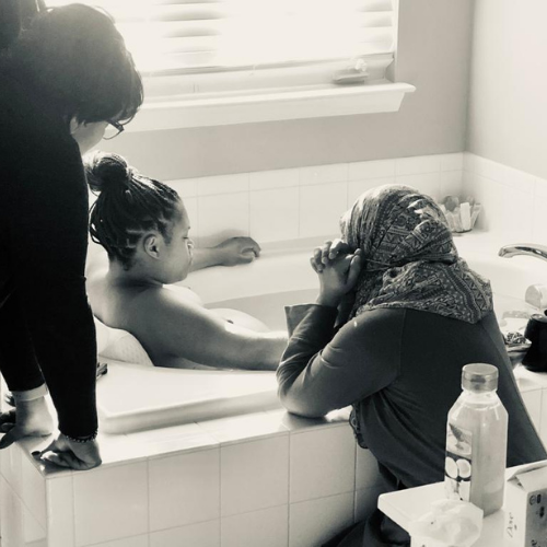 doula and mother supporting laboring person in tub